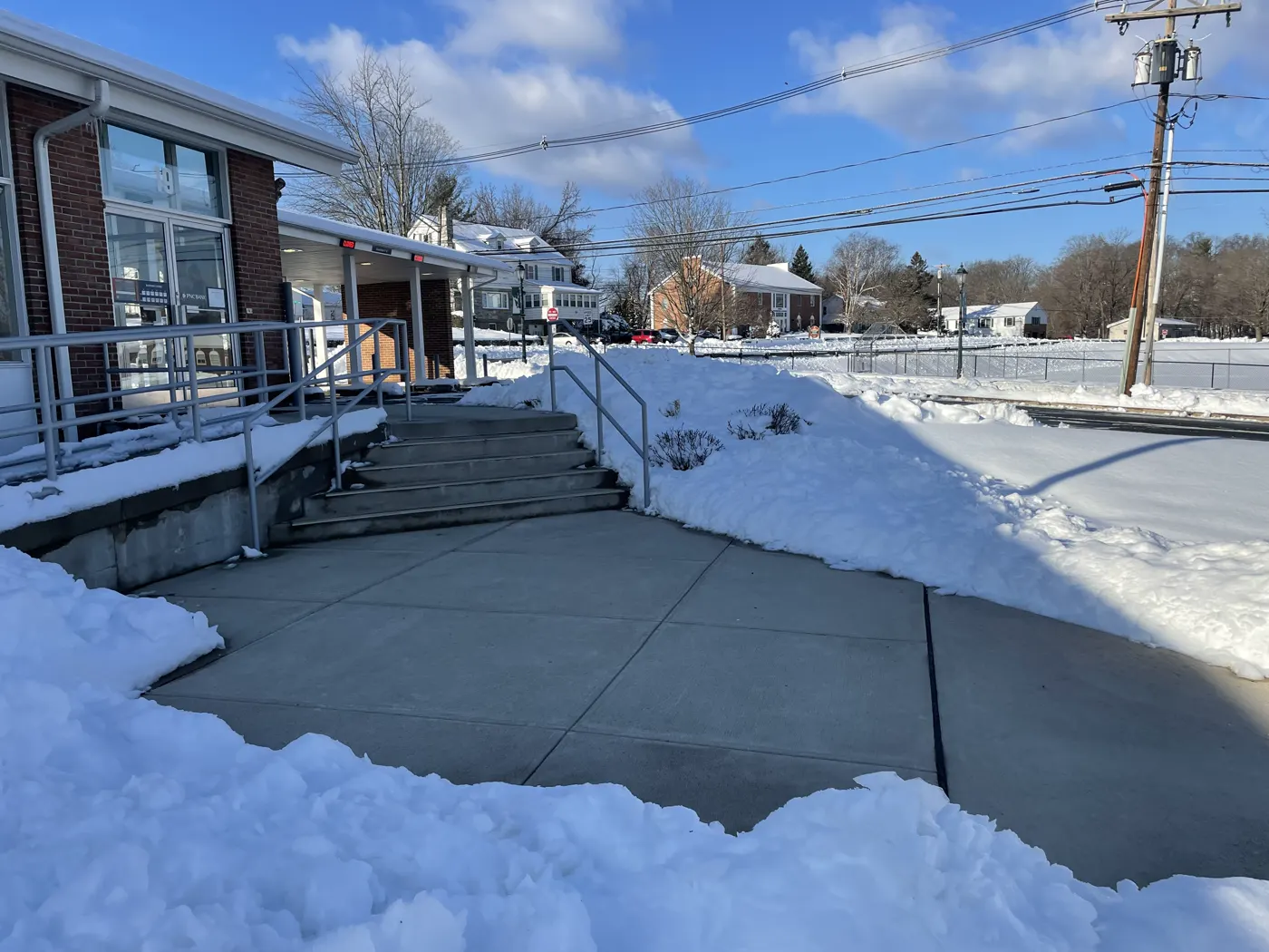 Cleared concrete walkway and ramp leading to a building entrance after a snowfall