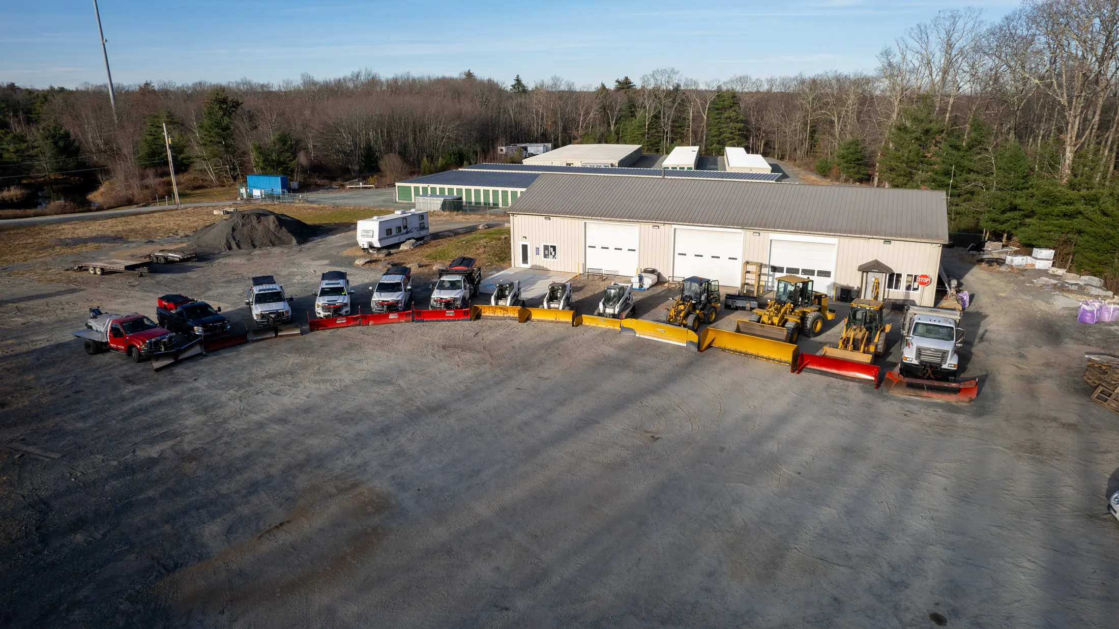 The Anthony Winter Services fleet of plow trucks and loaders lined up in front of the shop