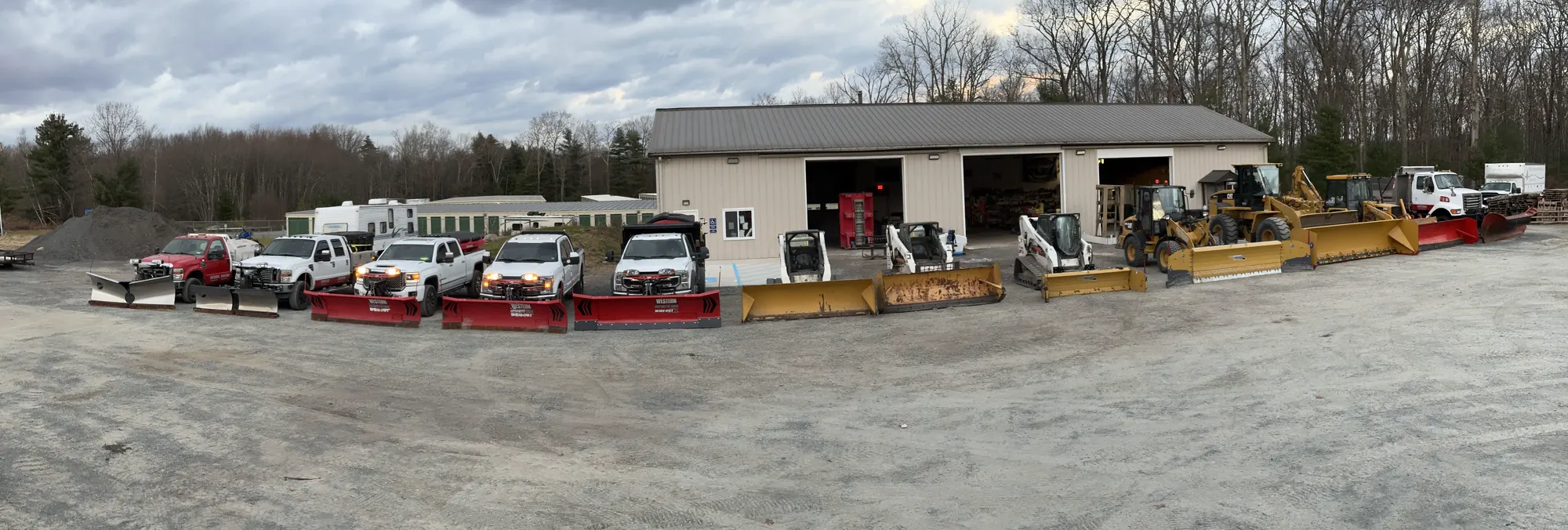 Plow trucks and loaders lined up in the yard in front of the Anthony Winter Services shop