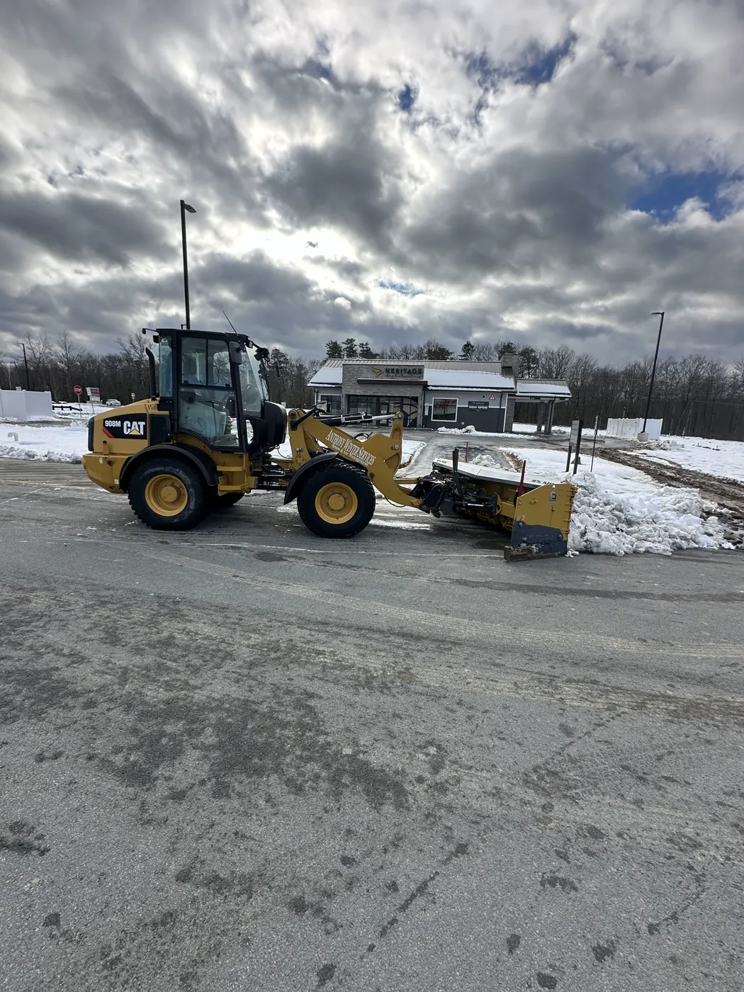 Yellow wheel loader parked on a cleared lot after a storm