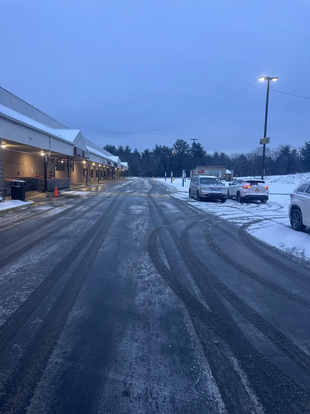 Cleared commercial drive and parking area at dusk with snowbanks along the curb