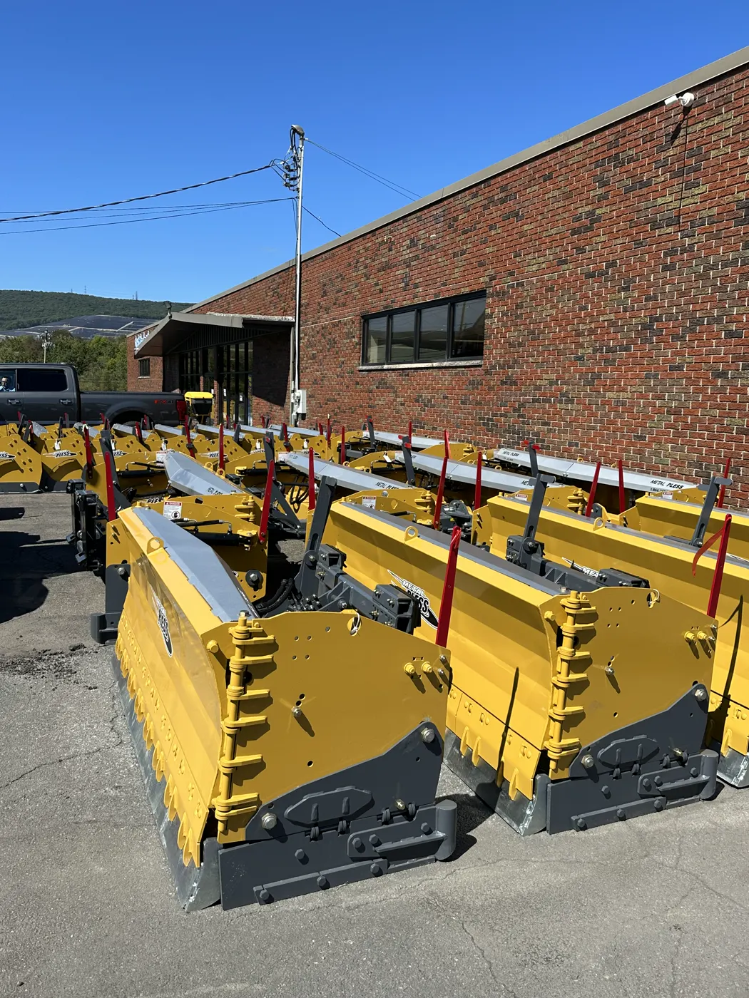 Row of yellow snow pushers lined up beside a brick building