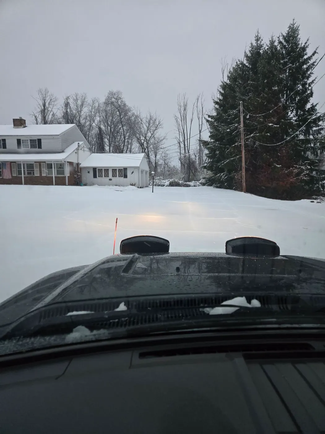 Plowed residential drive with houses and evergreens in the background