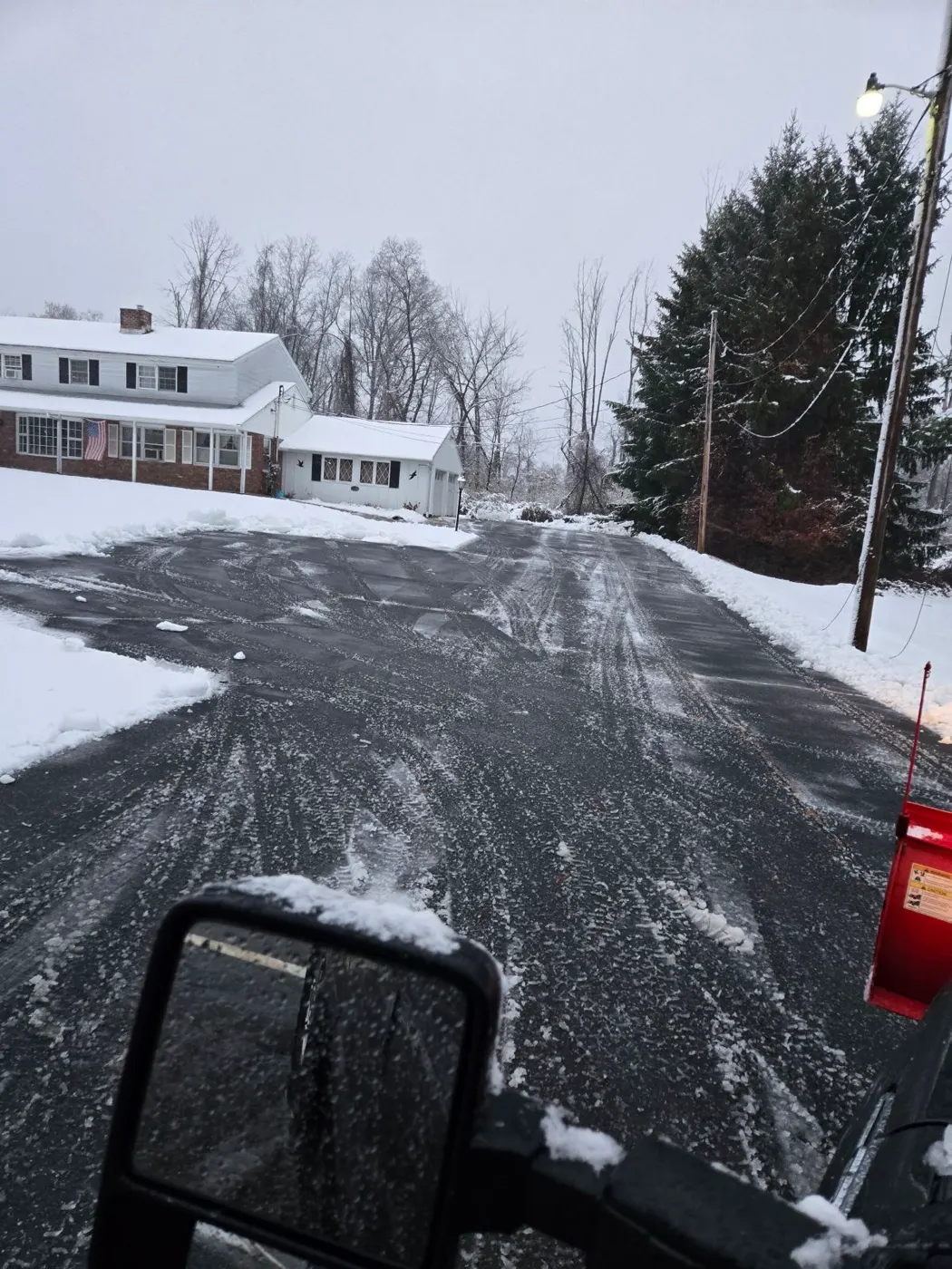 Freshly plowed residential driveway lined with snow-covered trees